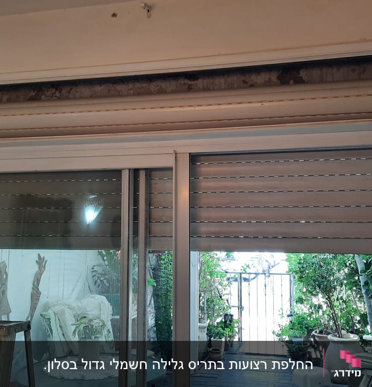 תריסים חצי פתוחים על חלון זכוכית גדול